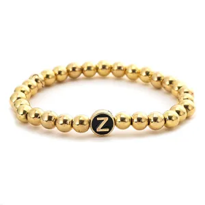 Detail of golden beaded stretch bracelet featuring a black round bead with letter Z