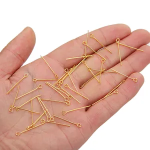 Gouden oogspelden voor sieraden maken vastgehouden in de hand voor de grootte