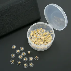 Macro detail of gold metal and clear plastic earring backings with storage box
