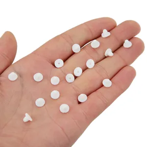 Macro detail of white silicone earring backings held in palm for size reference