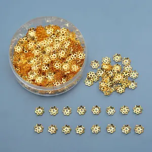 Golden flower-shaped alloy bead caps in a transparent storage box for jewelry DIY