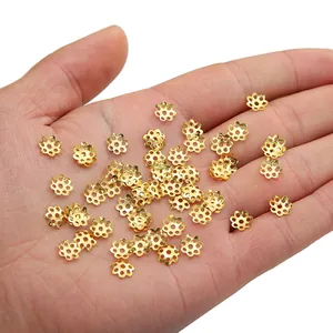Golden flower-shaped alloy bead caps for DIY jewelry making held in a hand