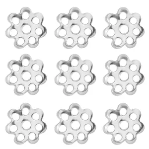 Macro detail of nine silver hollow flower spacer beads for DIY jewelry making