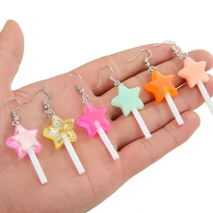 Boucles d'oreilles sucettes étoiles colorées en résine avec crochets argentés sur main