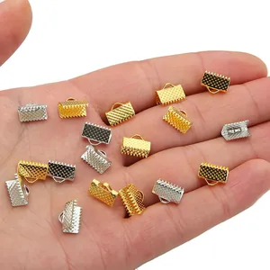 Makroaufnahme von gold- und silberfarbenen Bandklemmen für DIY-Schmuck in der Hand