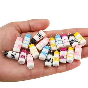 Colorful resin milk bottle pendants with metal rings shown in hand for scale