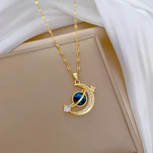 Gold celestial necklace featuring a zircon moon and blue planet pendant on silk fabric