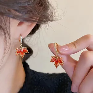 Dettaglio degli orecchini a foglia d'acero rossa con cristalli e finitura dorata