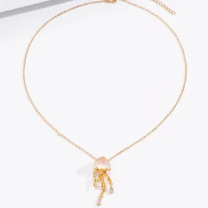 Close-up of a golden jellyfish pendant with pink resin and micro-pave crystals