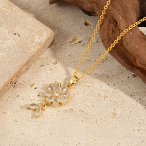 Elegant gold flower pendant necklace with white zircons on a natural stone background