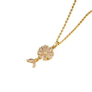 Gold floral pendant necklace with white zircon petals and leaf charm on a link chain