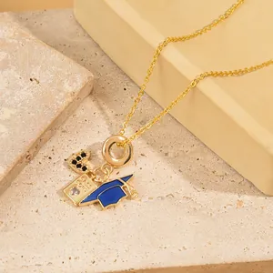Gold pendant necklace featuring a blue passport and graduation cap on textured stone