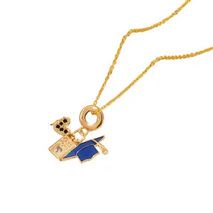 Gold pendant necklace featuring a black zircon heart, blue mortarboard, and passport charms