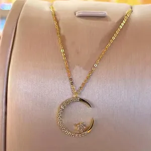 Gold crescent moon and star pendant necklace with white pavé zircons on display
