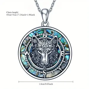 Détail d'un pendentif tête de loup avec incrustation d'abalone et marquages de boussole