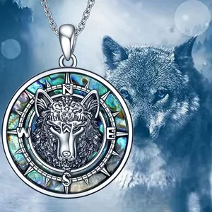 Détail macro du pendentif tête de loup argenté avec boussole et incrustation d'abalone