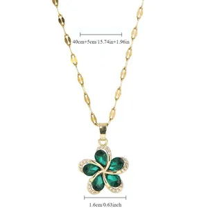 Detail view of a gold flower pendant with green stones and precise size markings