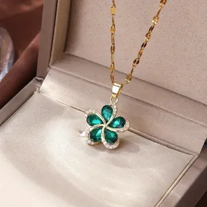 Detailed macro shot of a gold flower necklace featuring green stones in a luxury beige jewelry box