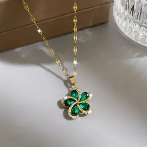 Close-up of gold flower pendant necklace with five green teardrop stones and white crystals