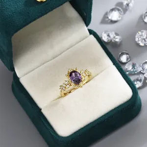 Elegant gold ring with oval purple crystal and micro-pave stones in a green velvet box