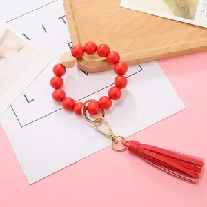 Macro detail of red wood bead bracelet keychain with gold ring and leather tassel