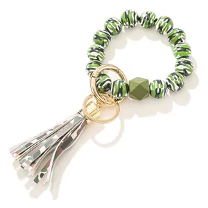 Detail von Camouflage-Holzperlen, goldenem Federring und Kunstleder-Quaste am Armband