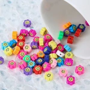 Détail de perles fleurs souriantes colorées en pâte polymère sortant d'un bol blanc