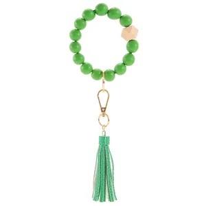 Close-up of green beaded wristlet keychain with wooden bead, gold clasp and leather tassel