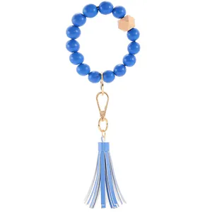 Detail of blue wooden bead keychain bracelet with leather tassel and gold metal clasp