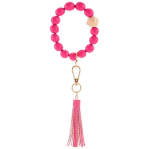 Close-up of bright pink wooden beaded bracelet keychain with gold clasp and leather tassel