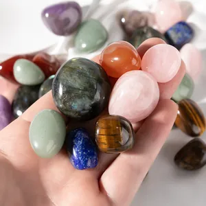 Polished natural crystal stones including rose quartz and tiger eye held in hand for scale