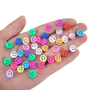 Gros plan de perles rondes colorées à visage souriant pour bijoux DIY dans une main