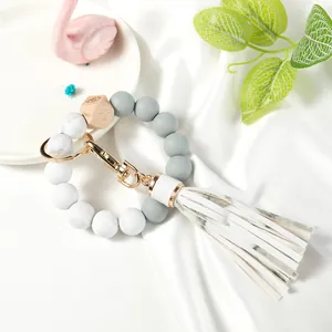Detail of beaded keychain bracelet with marble silicone beads and tassel on silk background