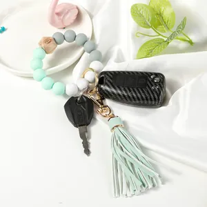 Detail of mint green silicone bead wristlet keychain with wood bead and leather tassel