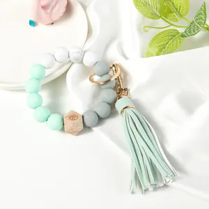 Detail of beaded keychain bracelet with mint green silicone beads and engraved wood bead