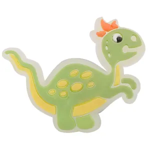 Detailansicht eines grünen Dinosaurier-Schuhanhängers aus PVC mit Schleife für Clogs