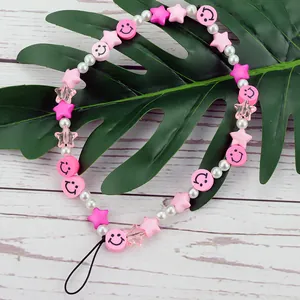 Detail shot of a handmade phone charm with pink smileys and stars on a leaf