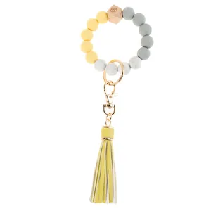 Detail of beaded wristlet keychain with silicone beads, wood bead, and yellow tassel
