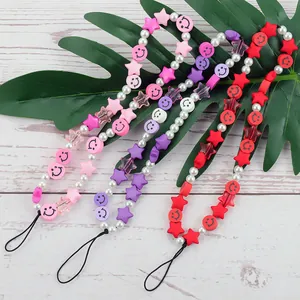 Handmade beaded phone charms with colorful stars, pearls and smiley faces on a leaf