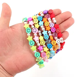 Hand holding colorful Y2K beaded phone straps with clay smiley faces and stars