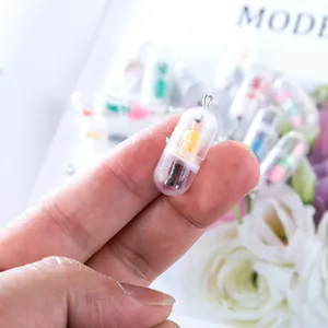 Close-up of a tiny pill capsule pendant featuring a miniature figure for DIY jewelry