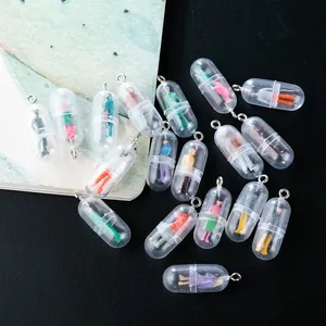 Macro detail of mini pill capsule charms with colorful miniature figures and metal rings