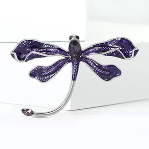 Detailed close-up of dragonfly brooch with purple enamel wings and faceted oval gemstone