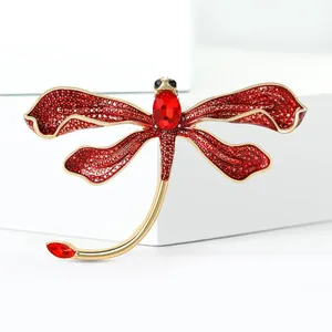 Detailed view of dragonfly brooch with red crystals and gold-plated enamel setting