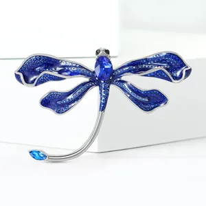 Detailed macro view of dragonfly brooch with blue enamel wings and sparkling rhinestones