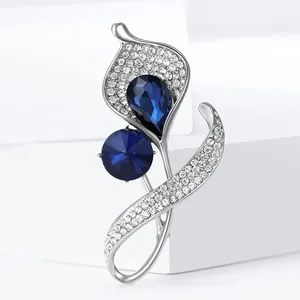 Elegant rhinestone orchid flower brooch with blue gemstones on white geometric pedestal