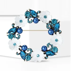 Broche couronne florale élégante avec fleurs émaillées blanches, cristaux bleus et perles