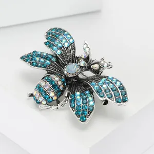 Exquisite silver alloy bee brooch with blue rhinestones and iridescent crystals on white stand
