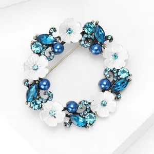 Détails macro de la broche couronne avec fleurs blanches, perles bleues et strass