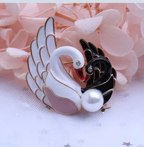 Detalle del broche de doble cisne con esmalte blanco y negro y una gran perla central